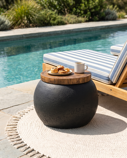 Black concrete ball side table with wood top poolside beside a lounger