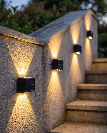 Solar up/down wall lights washing a stone garden wall at dusk