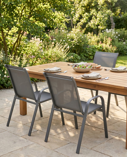 Grey textilene high-back patio dining chairs at a set table in a garden