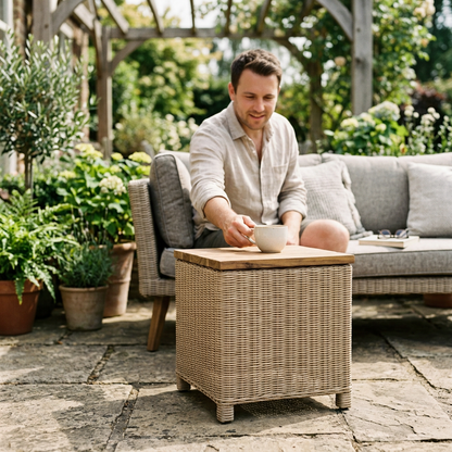 Father setting a coffee cup on a rattan patio side table with acacia top