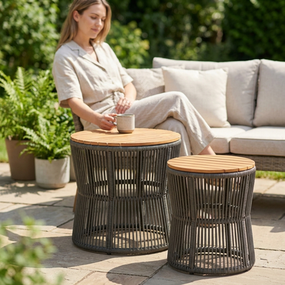 Pair of round nesting rattan side tables with wooden tops on a patio